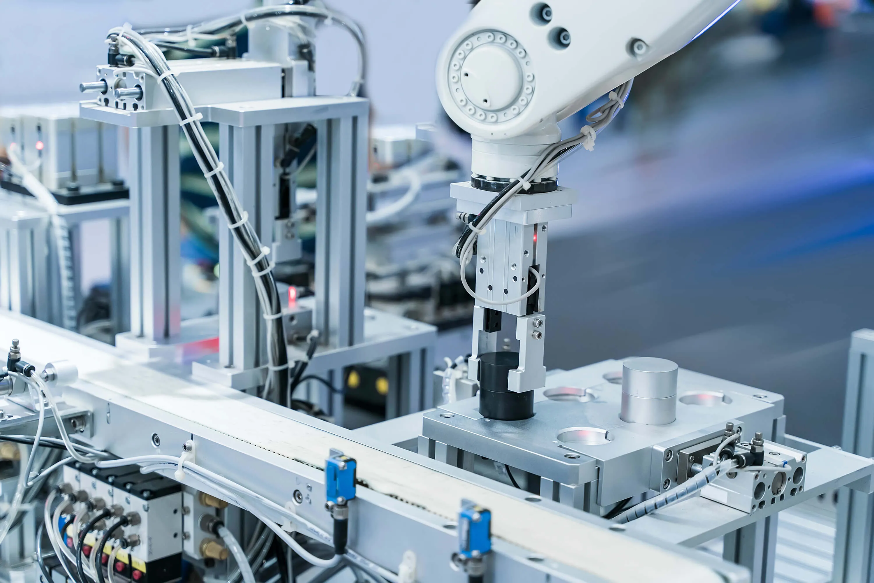 Ein Roboterarm setzt ein Bauteil in eine Montagestation aus Aluminiumprofilen